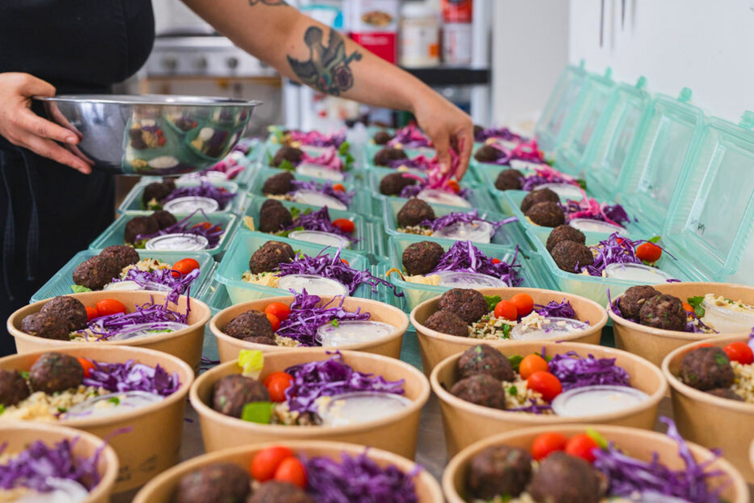 Meal prep in The Conscious Farm Kitchen. Celeste is adding pickled red onions to our falafel bowls.
