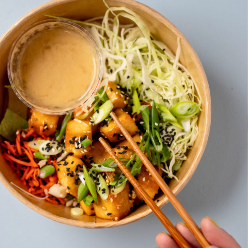 Overhead shot of an Asian tofu bowl being eaten with chop sticks.