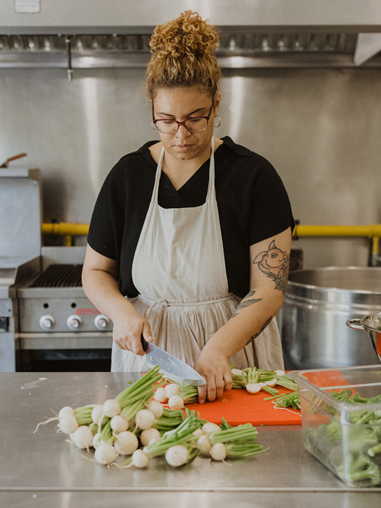 The Conscious Farm Kitchen owner, Celeste in the kitchen chopping organic spring onions.