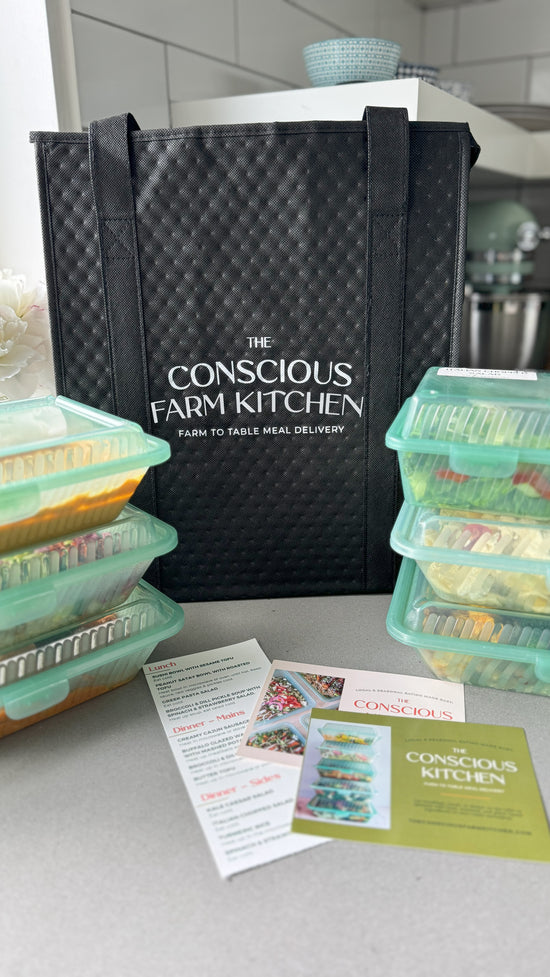 The Conscious Farm Kitchen delivery cool bag with prepared meals stacked next to it in reusable containers.